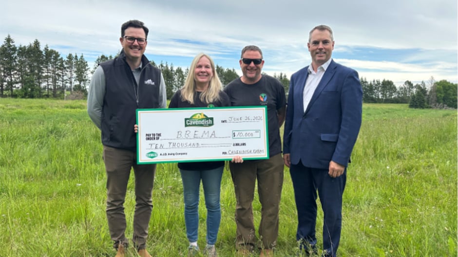 Four people in a grassy field hold a Cavendish cheque for $10,000 awarded to BBEMA.